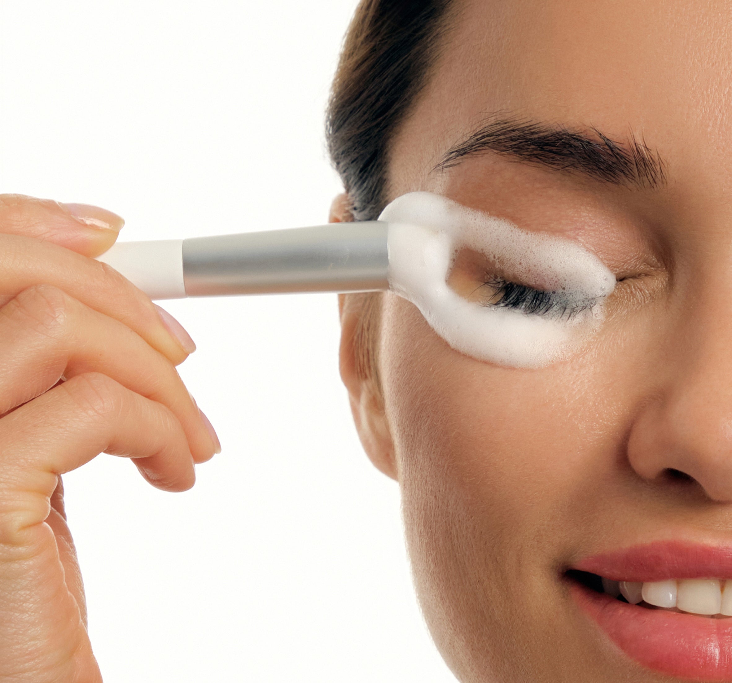 a woman brushing her lashes with foaming cleanser
