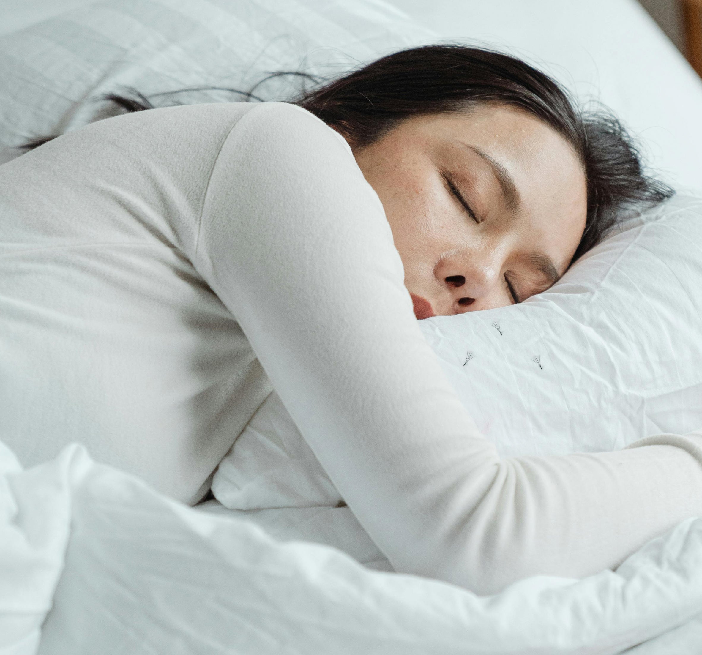 a woman sleeping with her head on the pillow