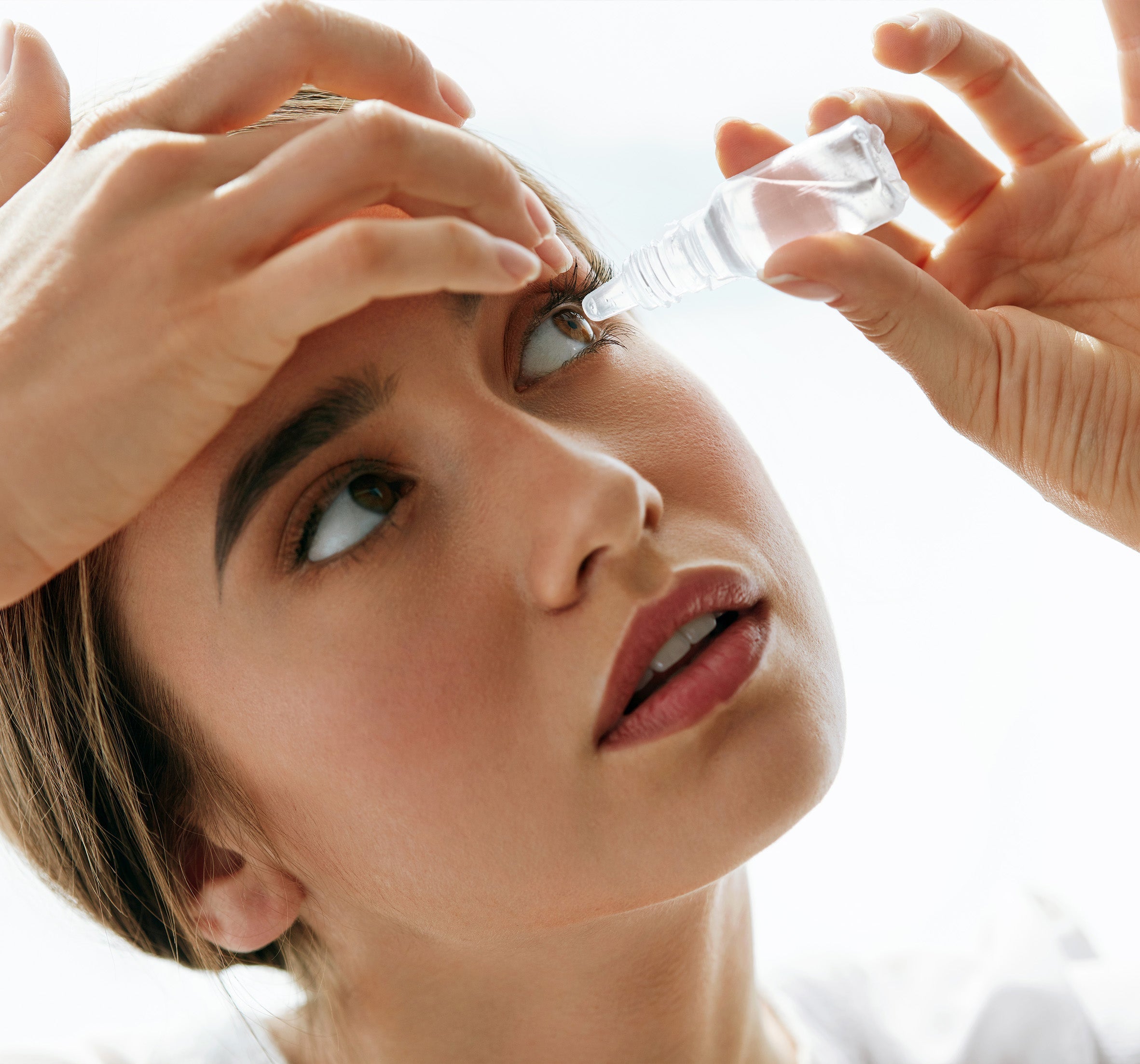 a  woman using eye drops