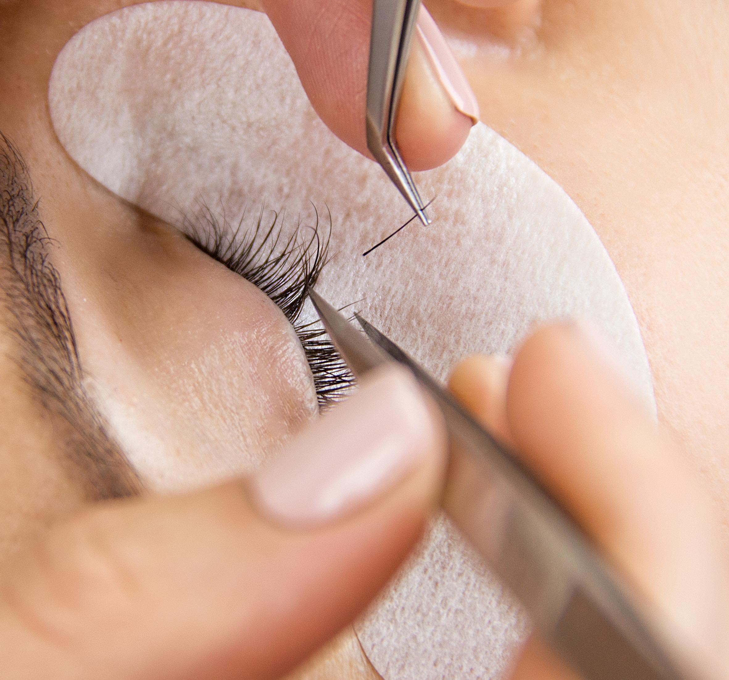 closeup of an eye while applying lash extensions